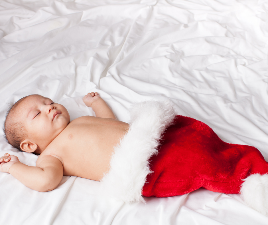 Holiday Sleep Struggles image of a young baby asleep inside a red Santa hat